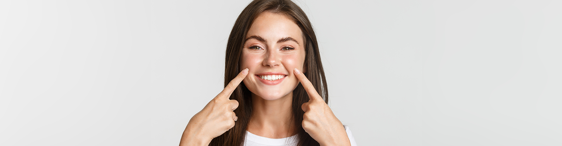 Woman pointing at her smile.